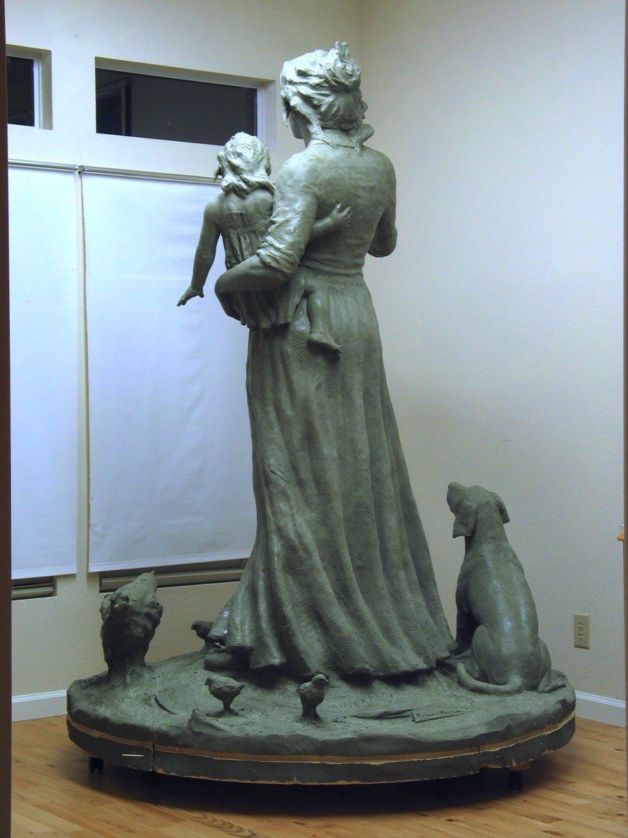 Rear view of completed clay sculpture of pioneer, child. dog and chickens.